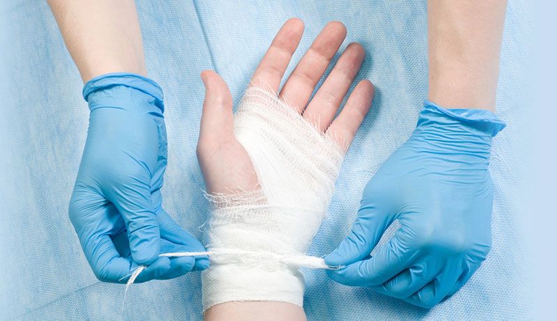 Gloved hands bandaging a patient’s hand